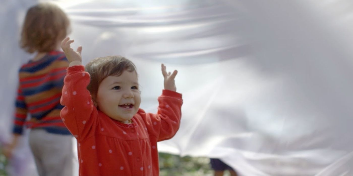 A child and a toddler play under a white sheet in The Beginning Of Life