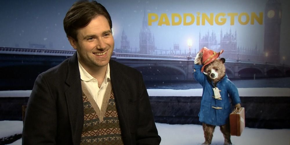 A split image of Paul King laughing in front of a Paddington poster