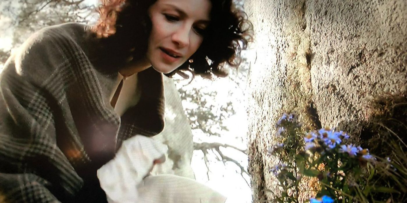 Claire collecting forget-me-nots by the stones in Outlander