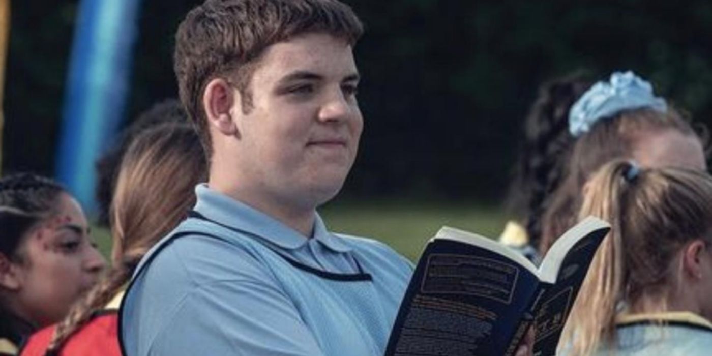 Isaac smiling while holding an open book in Heartstopper.