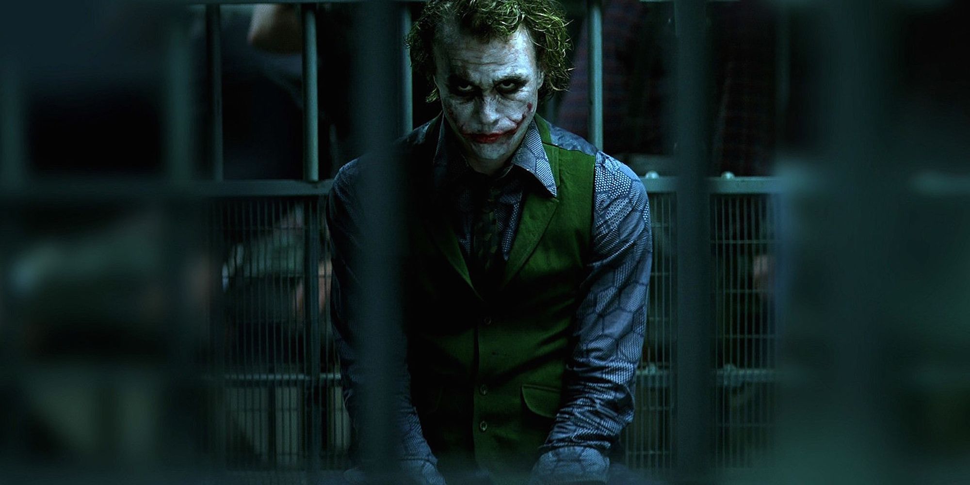 Heath Ledger as The Joker sitting in a cell in The Dark Knight