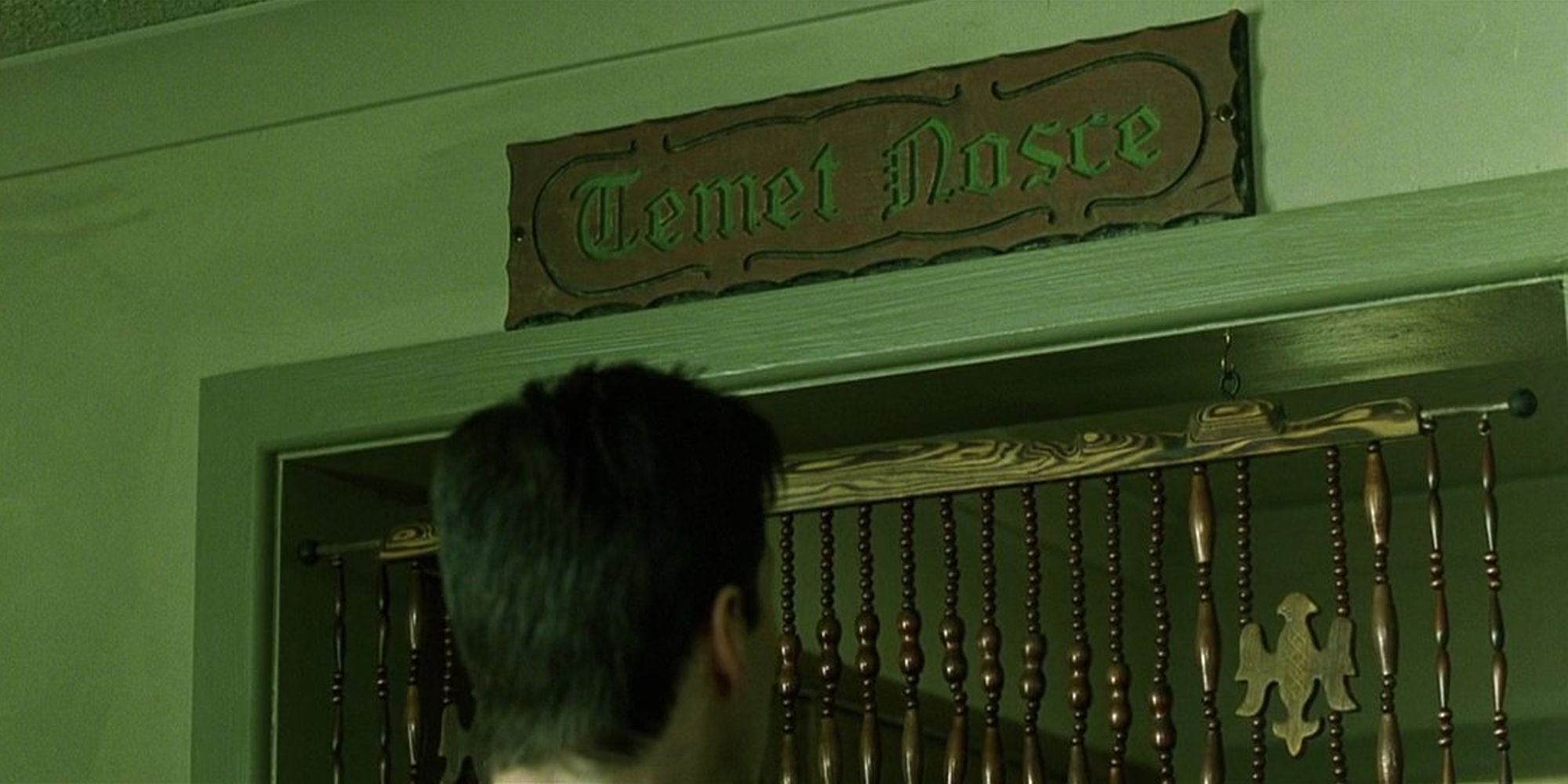 Neo looking at The Oracle's temet nosce sign.