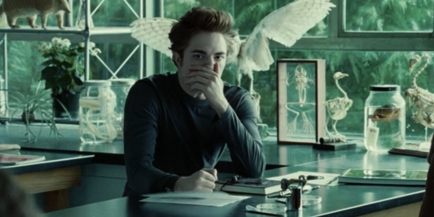 Edward Cullen sitting in a classroom covering his nose and mouth in Twilight