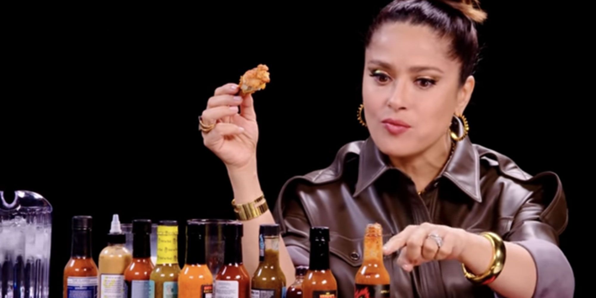 Salma Hayek holding a chicken wing on Hot Ones