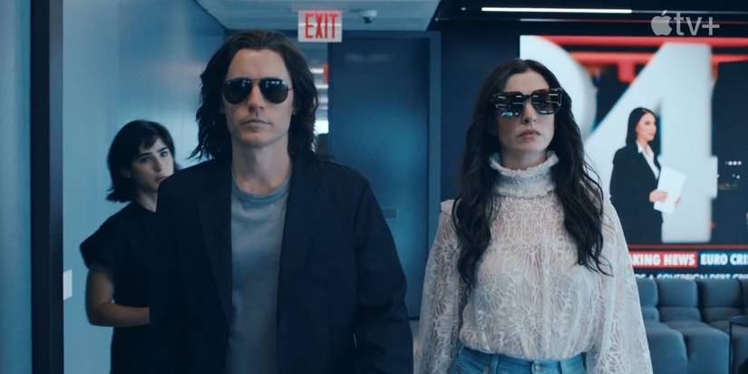 Jared Leto as Adam and Anne Hathaway as Rebekah walking into a room, each wearing sunglasses, in WeCrashed.