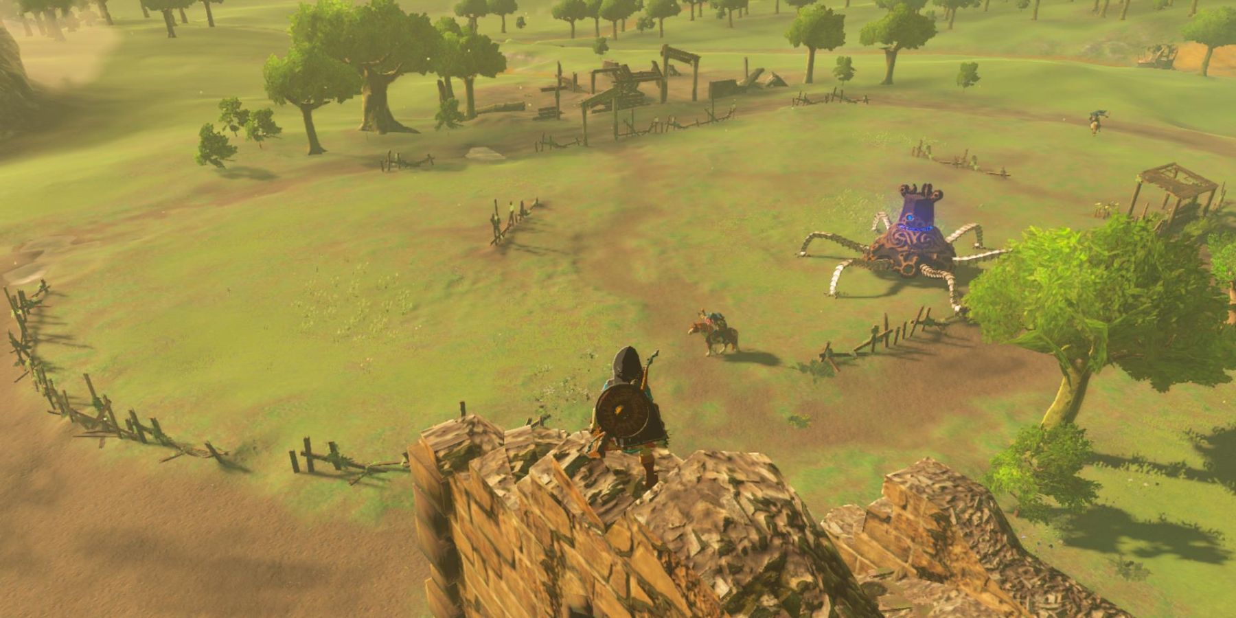 Link no topo do Breath of the Wild's Ranch Ruins olhando sobre os campos com um monstro mecânico 