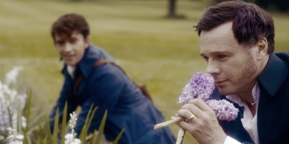 Edmund smells flowers outdoors in Bridgerton