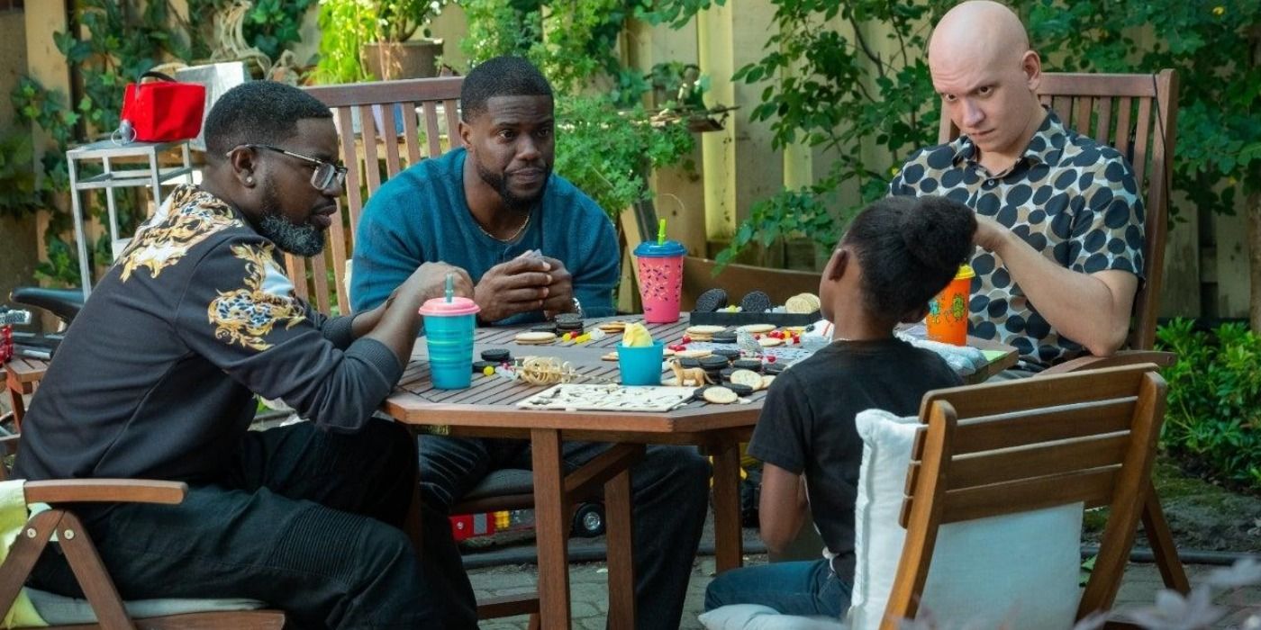 Lil Rel Howery sitting at a table with Kevin Hart in Fatherhood.