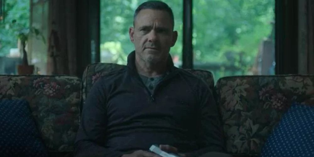 Nelson sits on a sofa with a gun in Ozark