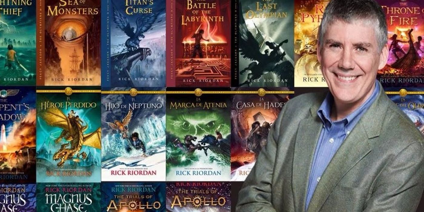 O autor de Percy Jackson, Rick Riordan, sorrindo na frente de seus livros.