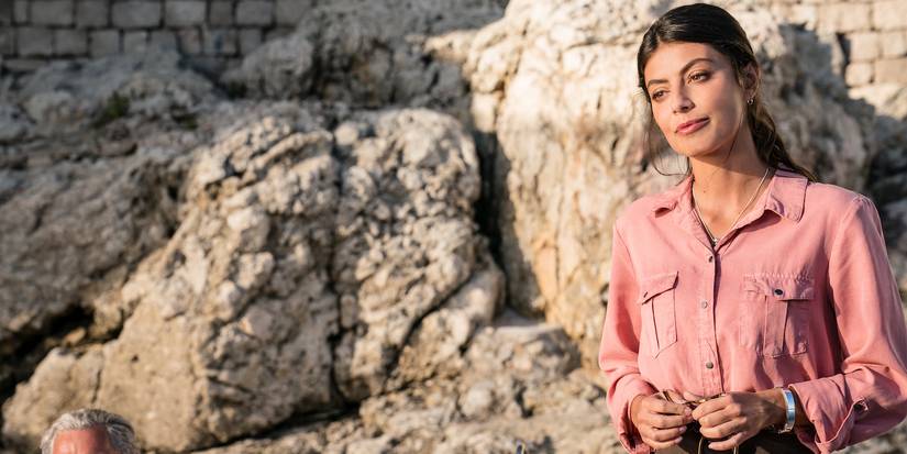 Gabriella standing by a rock wall in Unbearable Weight of Massive Talent.