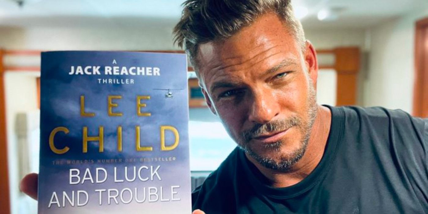 Alan Ritchson of Reacher holds up a copy of Lee Child novel 