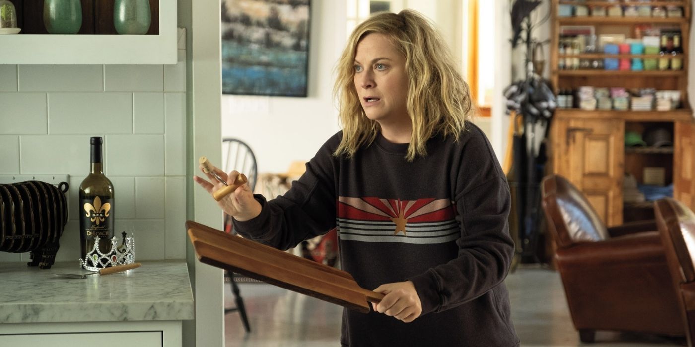 Amy Poehler as Abby with a wooden paddle looking nervous in Wine Country.
