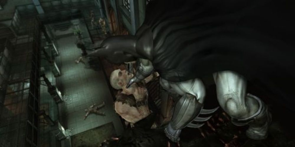 Batman grabs a thug by the throat in Arkham Asylum