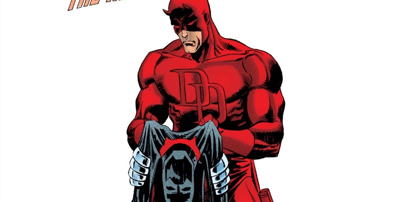 Daredevil, clad in his classic red costume, holds his red and black armored costume towards the foreground.