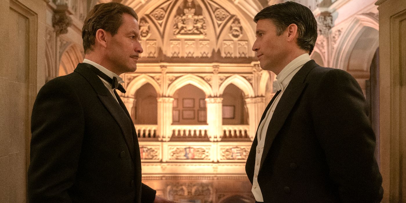 Two men talk in a doorway in front of a large church in Downton Abbey: A New Era