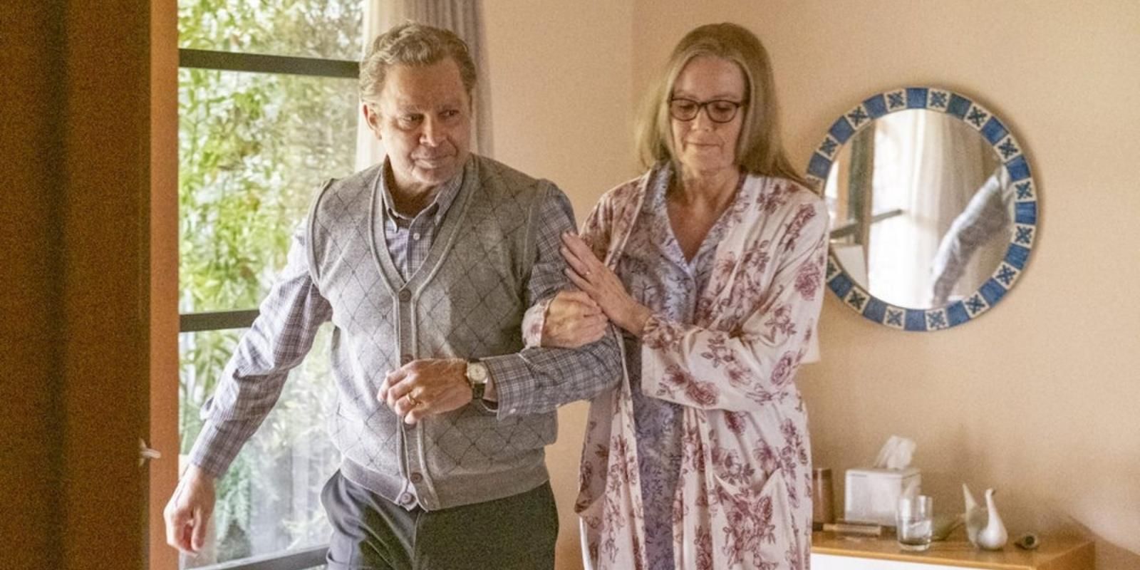 Elderly Miguel Rivas helps elderly Rebecca Pearson Rivas out of bed in This Is Us