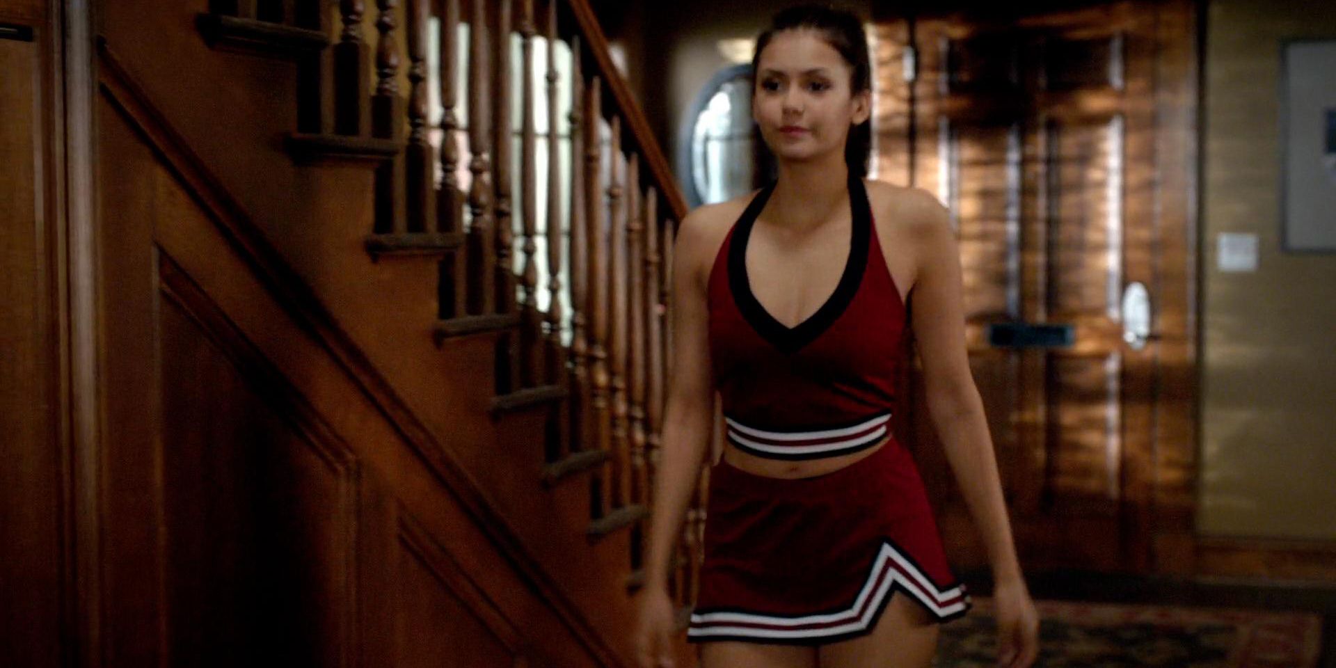 Elena Gilbert in her cheer-leading costume on The Vampire Diaries coming down the stairs looking serious.