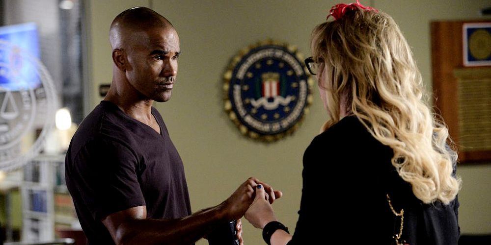 Image of Derek Morgan and Penelope Garcia on Criminal Minds, he's holding her hand between them and they're talking.