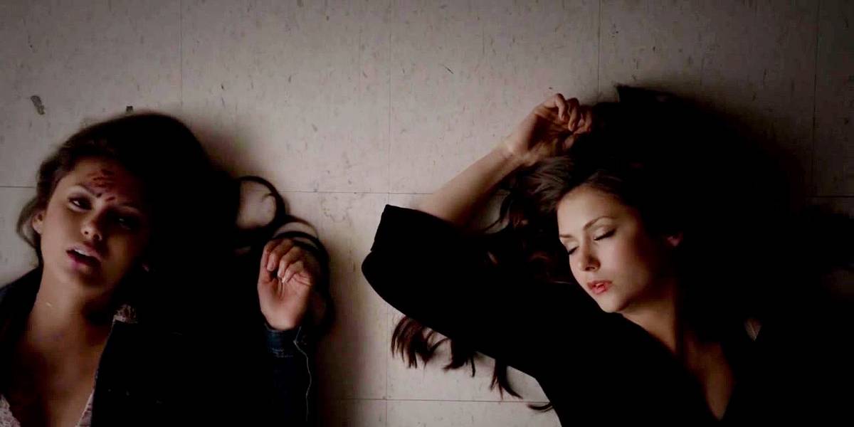 Imagem de Elena Gilbert e Katherine Pierce em The Vampire Diaries, ambas estão ensanguentadas e no chão depois que Elena acabou de dar a Katherine a cura para se salvar.