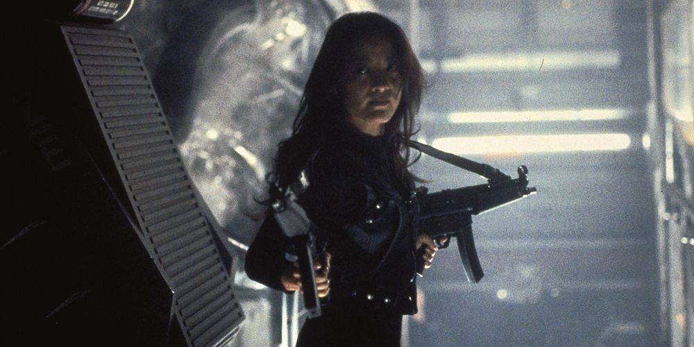 Michelle Yeoh holding two machine guns in Tomorrow Never Dies