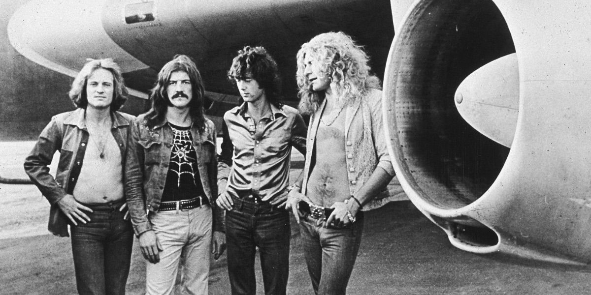 Led Zeppelin pose in front of an airplane