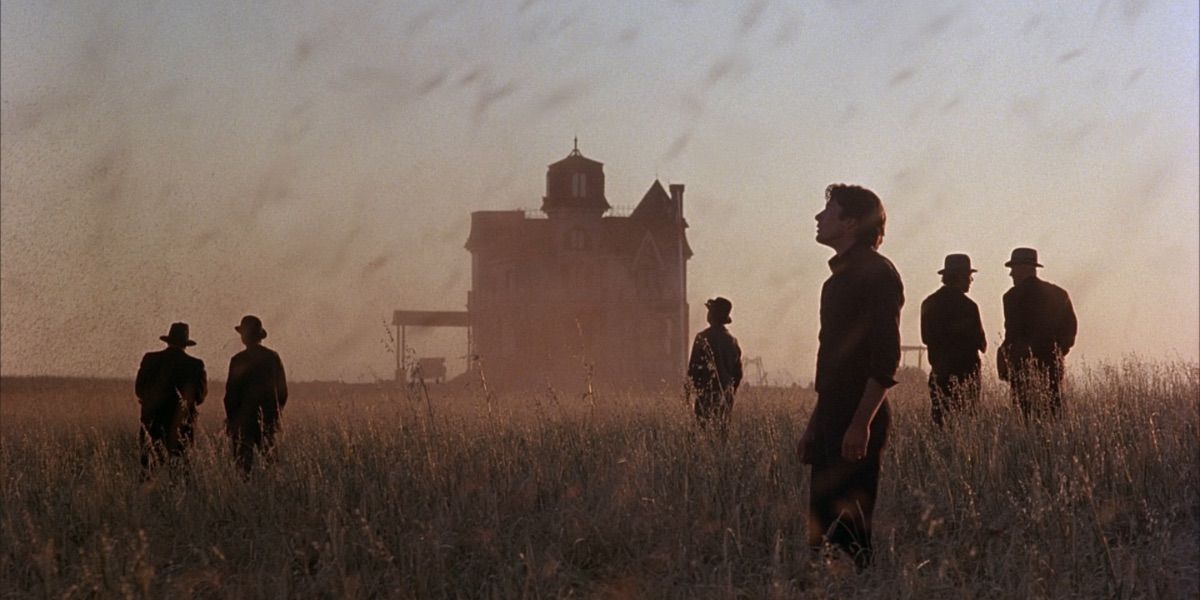 A group of people stand in a field in front of a farmhouse from Days of Heaven