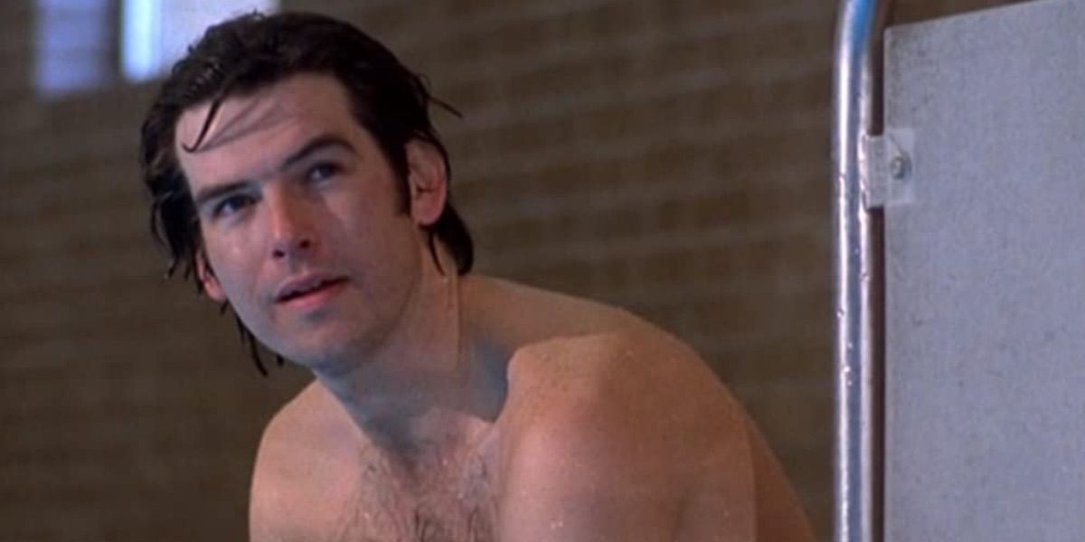 Pierce Brosnan looks on while sitting on the edge of a pool from the Long Good Friday