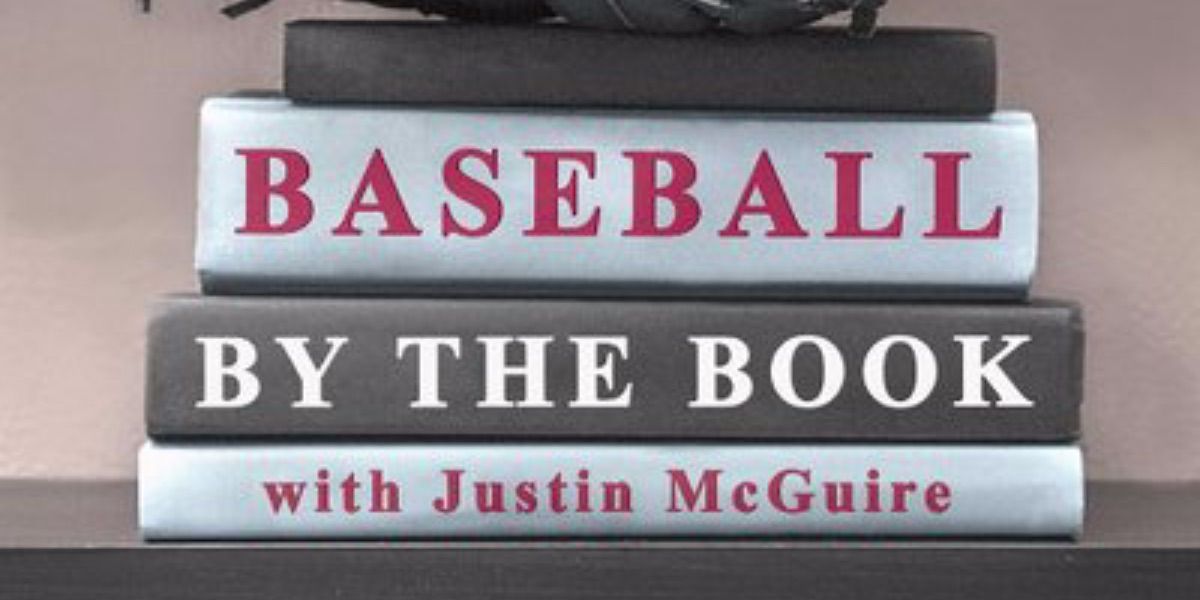 A pile of books stacked with the words Baseball by the Book