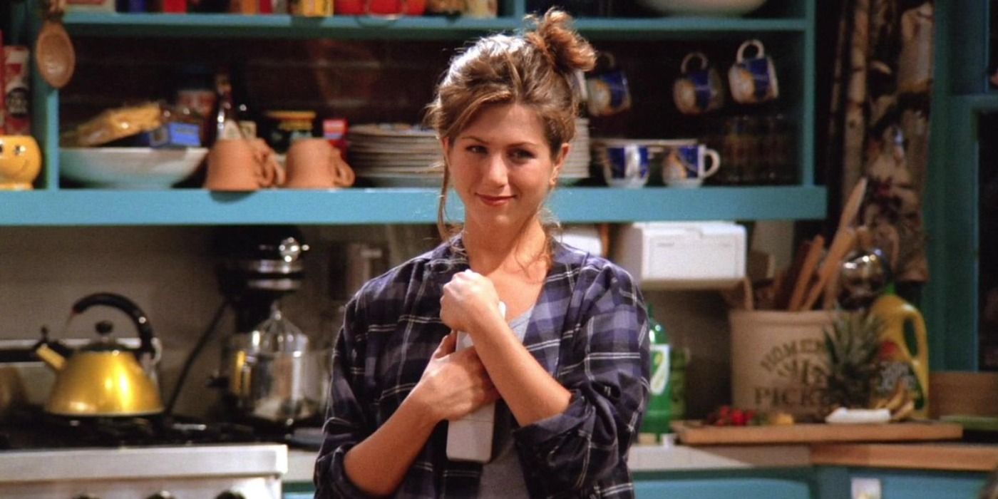 Rachel Green segurando um telefone nas mãos em seu apartamento em Friends.