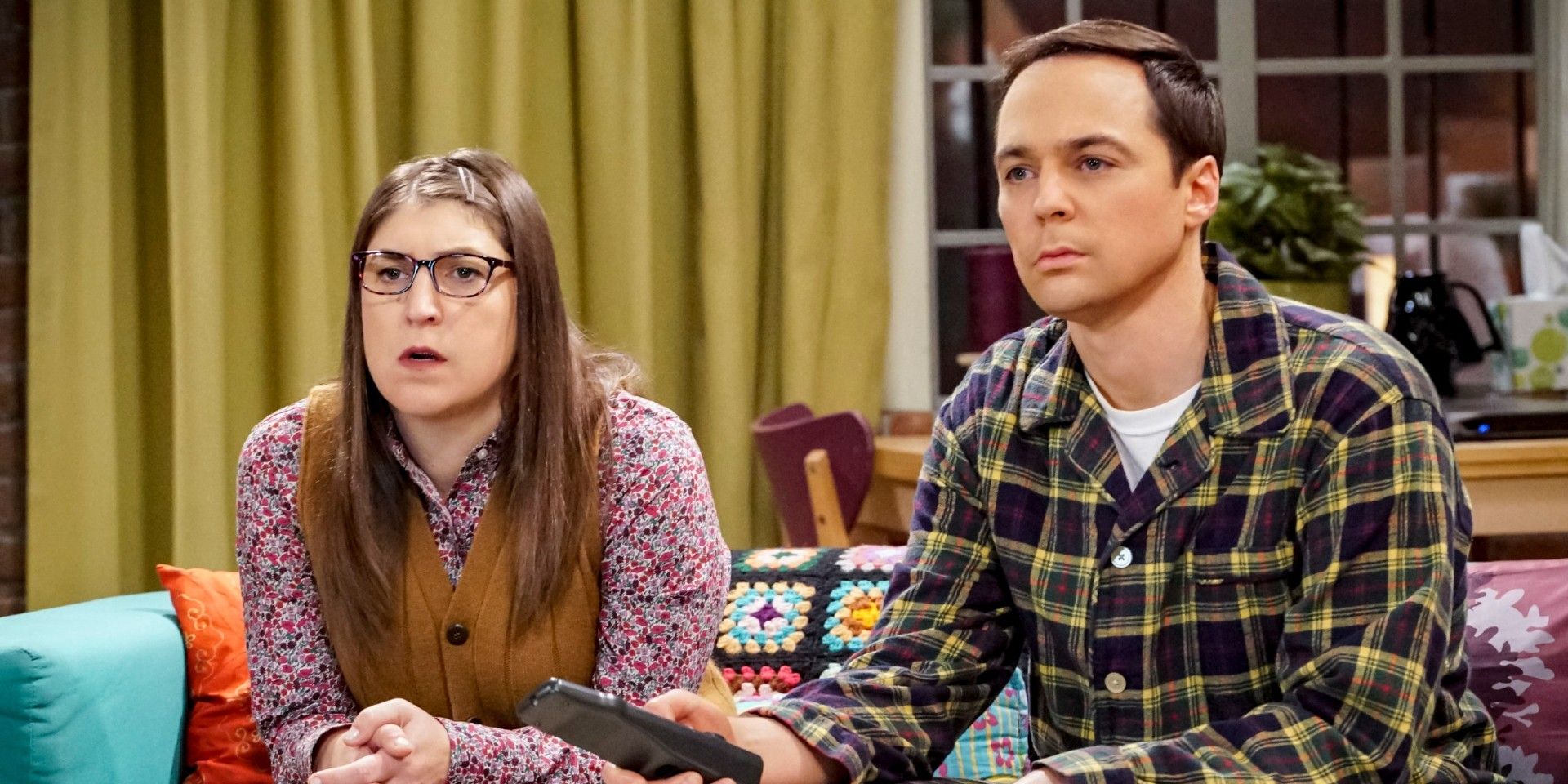 Amy e Sheldon sentados um ao lado do outro e olhando para longe com expressões confusas em The Big Bang Theory