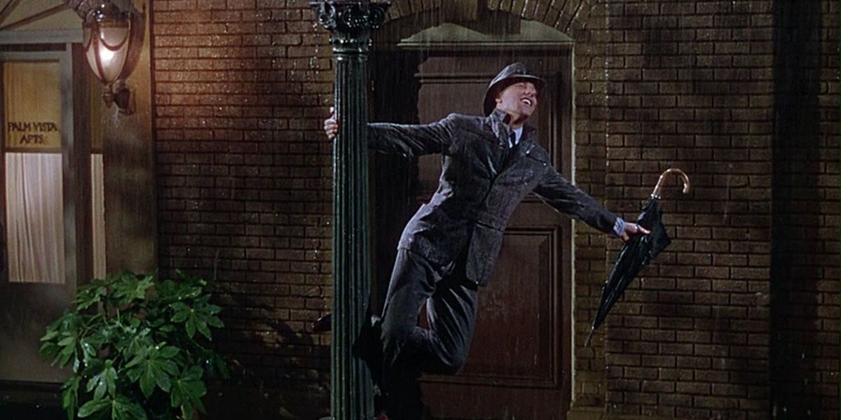 Don Lockwood dancing outside in the rain while holding an umbrella