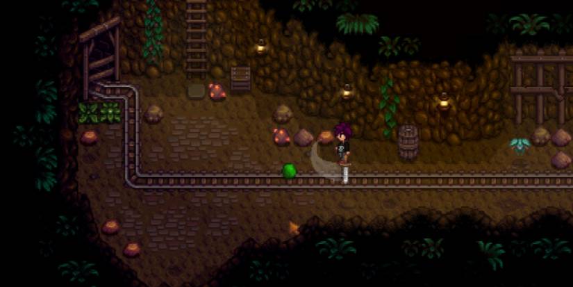A charcter swings a sword at a green slime in the mines from Stardew Valley.