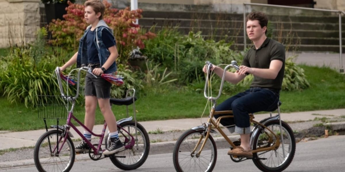 The Hardy boys riding their bikes on the street in The Hardy Boys (2020-)