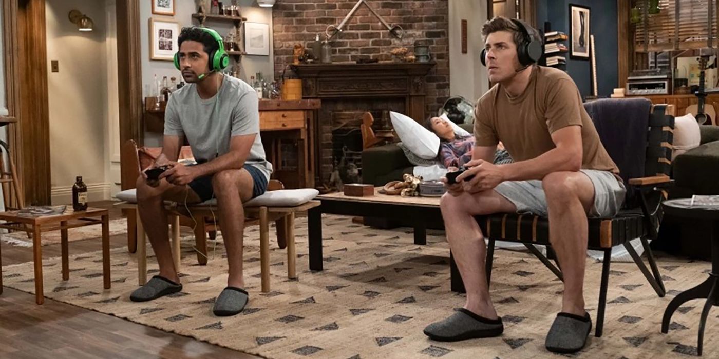 Jesse and Sid from How I Met Your Father sitting together playing video games in their apartment.