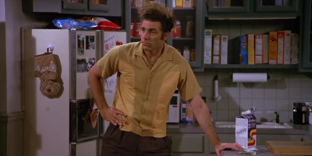 Kramer holds one hand on his waist and another on the kitchen counter in Seinfeld