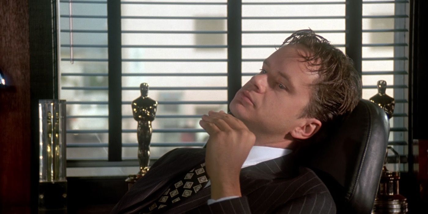 Tim Robbins reclining in a chair with an Oscar in the background in The Player.
