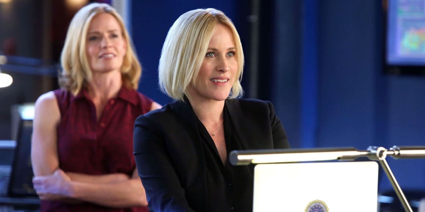Avery sits in front of a computer with a smile on her face while Julie crosses her arms and pensively looks on in the background in CSI: Cyber
