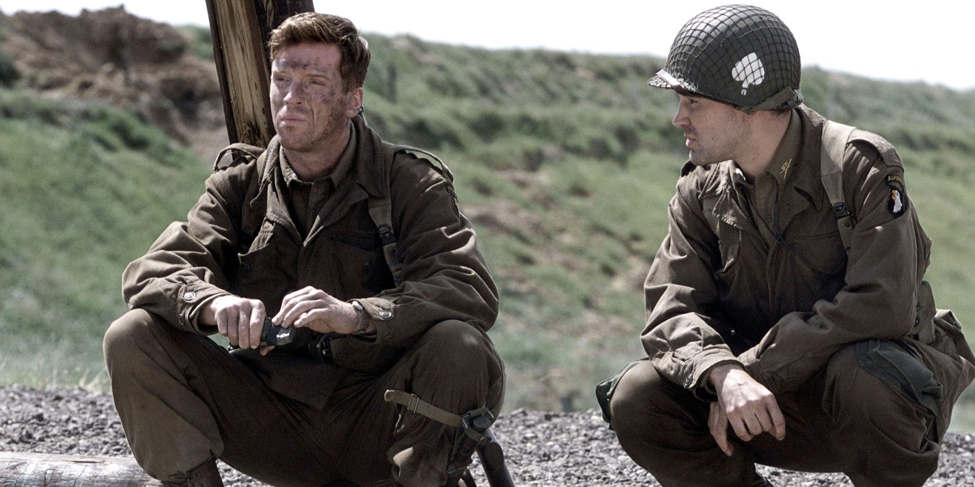 Two soldiers have a conversation while squatting in Band of Brothers.