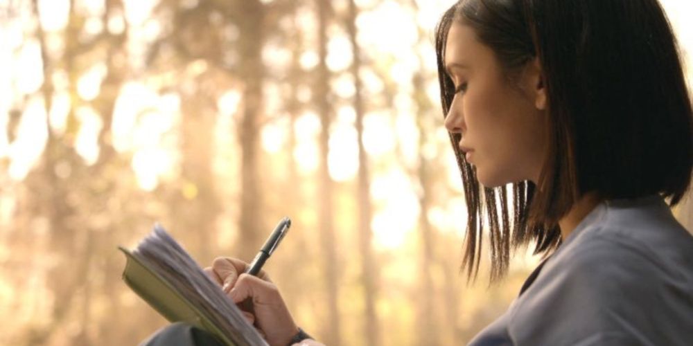 Elena Writing in a Cemetery in The Vampire Diaries finale