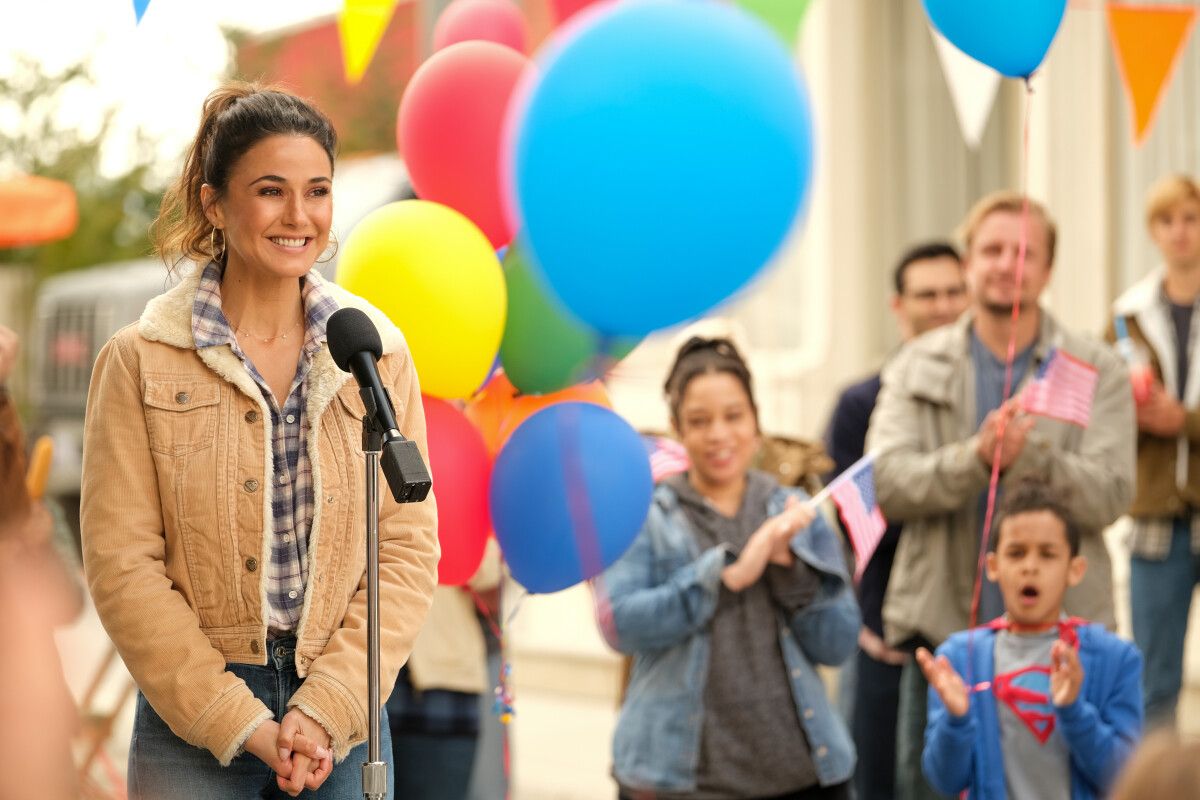 Emmanuelle Chriqui as Lana Lang smiling standing in front of a microphone in Superman and Lois season 2