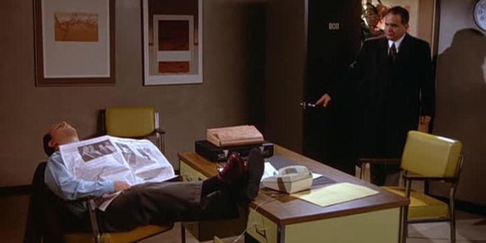 George asleep at his desk as Mr Tuttle walks in to the office on seinfeld