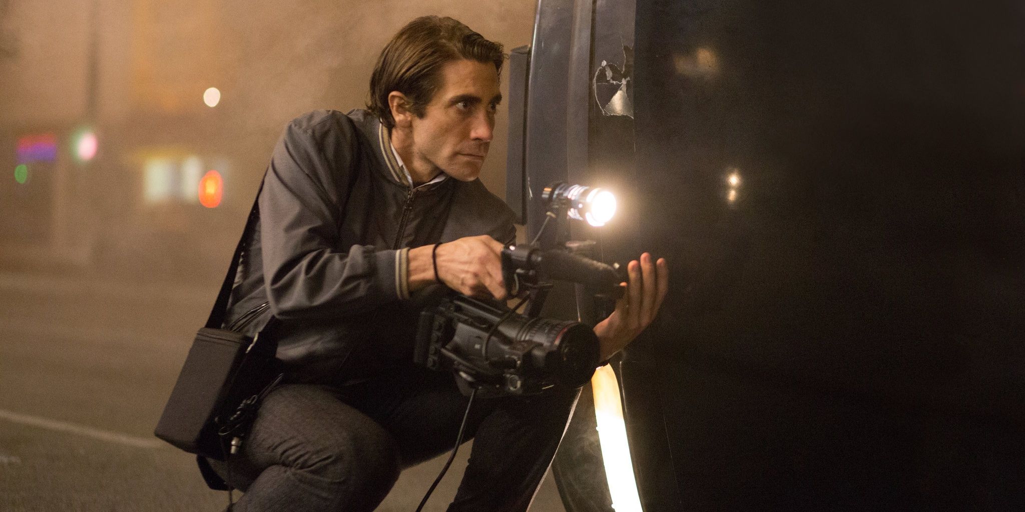 Jake Gyllenhaal crouching with a camera in LA in Nightcrawler