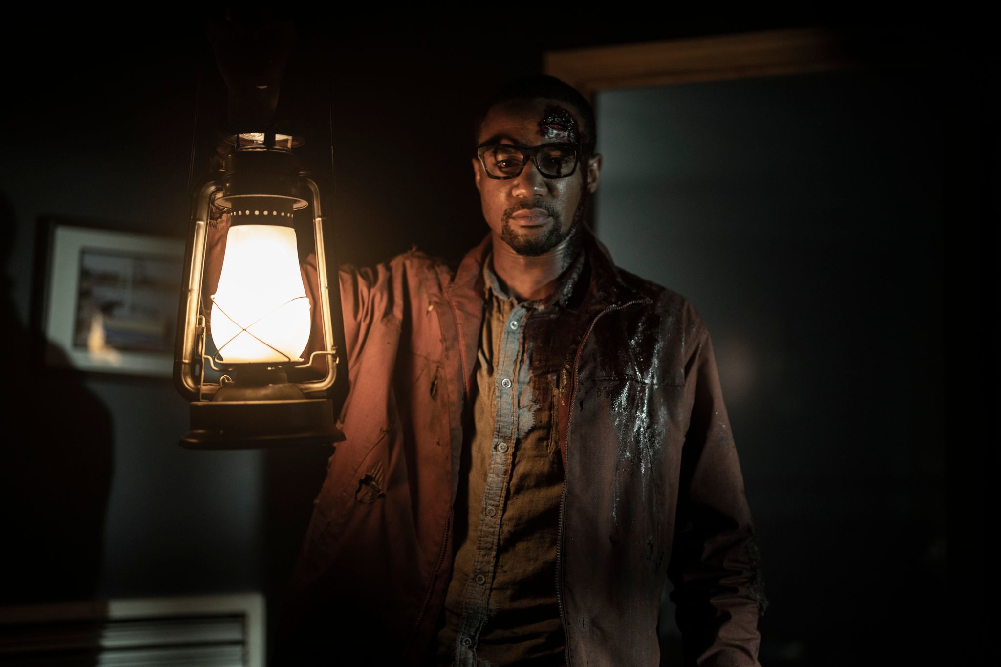 Jessie T. Usher in character as Davon in Tales of the Walking Dead holding up a lantern in a dark room