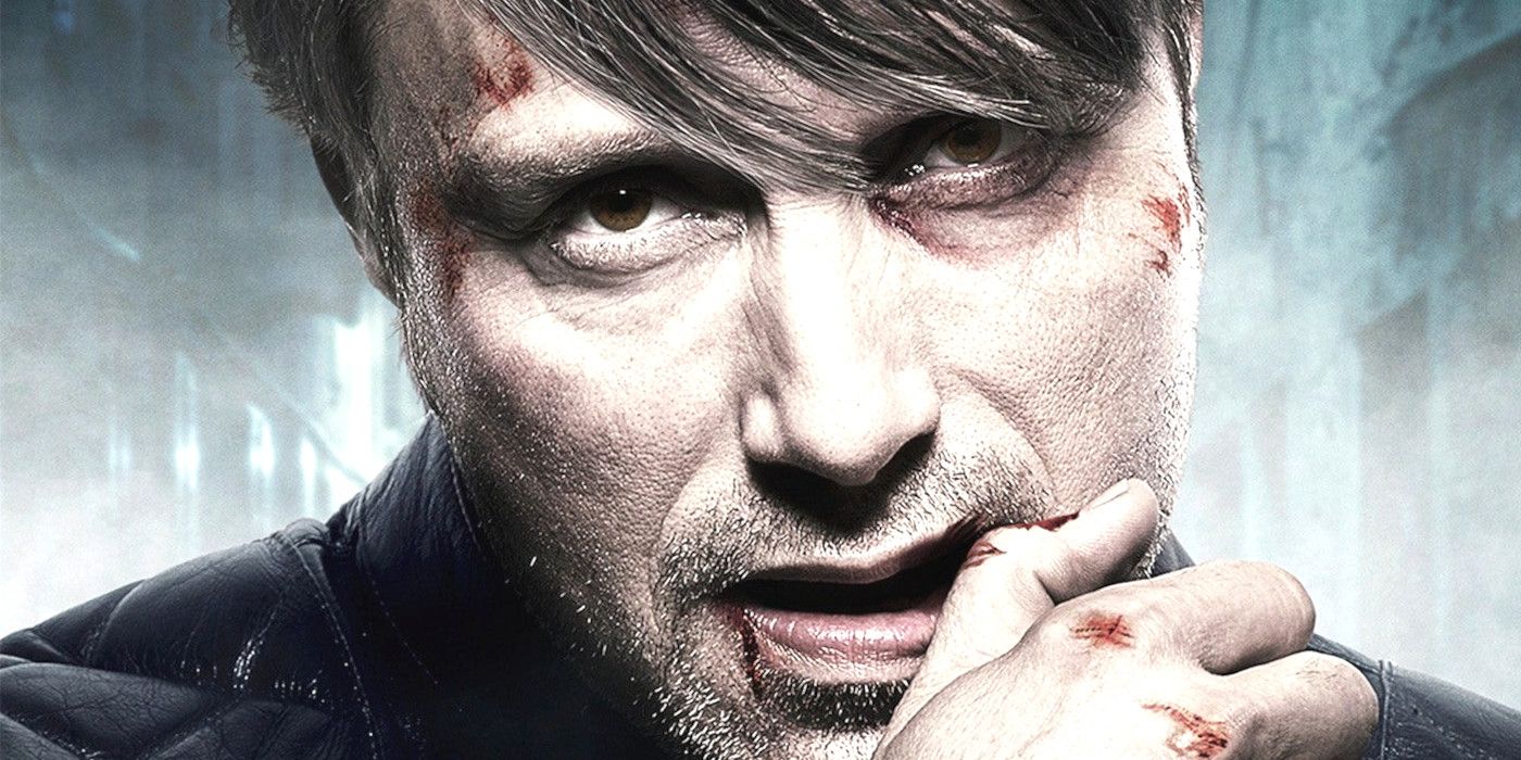 Close up of Mads Mikkelsen in character as Hannibal Lecter in Hannibal with scraped knuckles wiping his lip and glaring forward