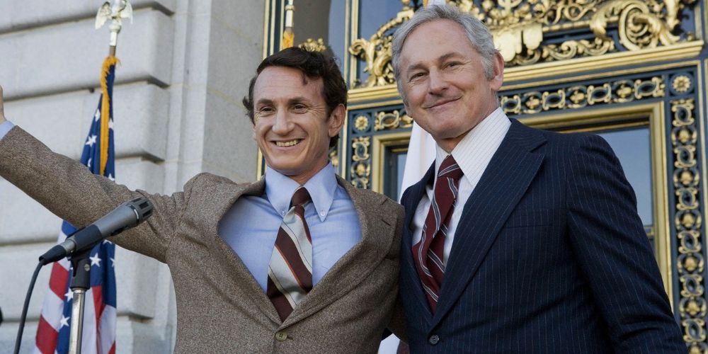 Sean Penn stars as Harvey Milk and stands at the podium of a political speech