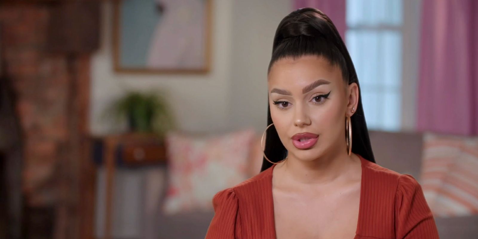 Miona Bell 90 Day Fiance Season 9 confessional wearing brown top high pony