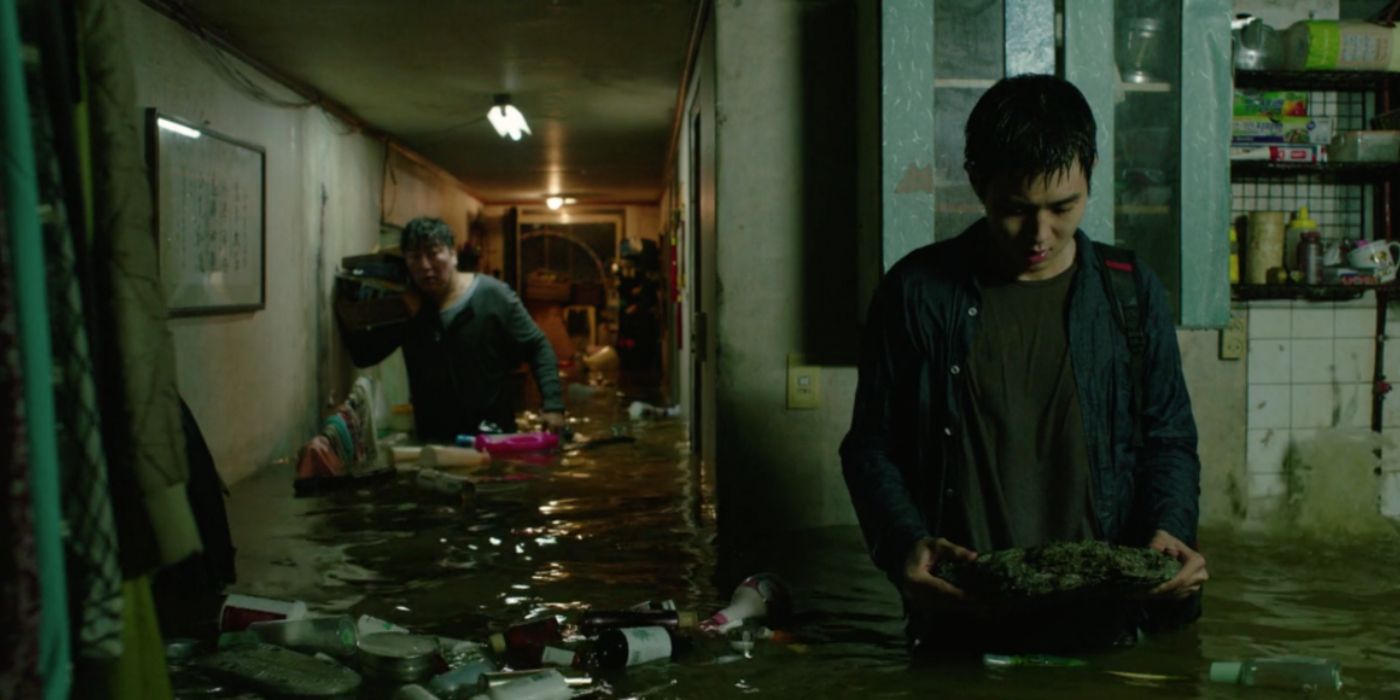 Mr. Kim and his son wading through their flooded home in Parasite