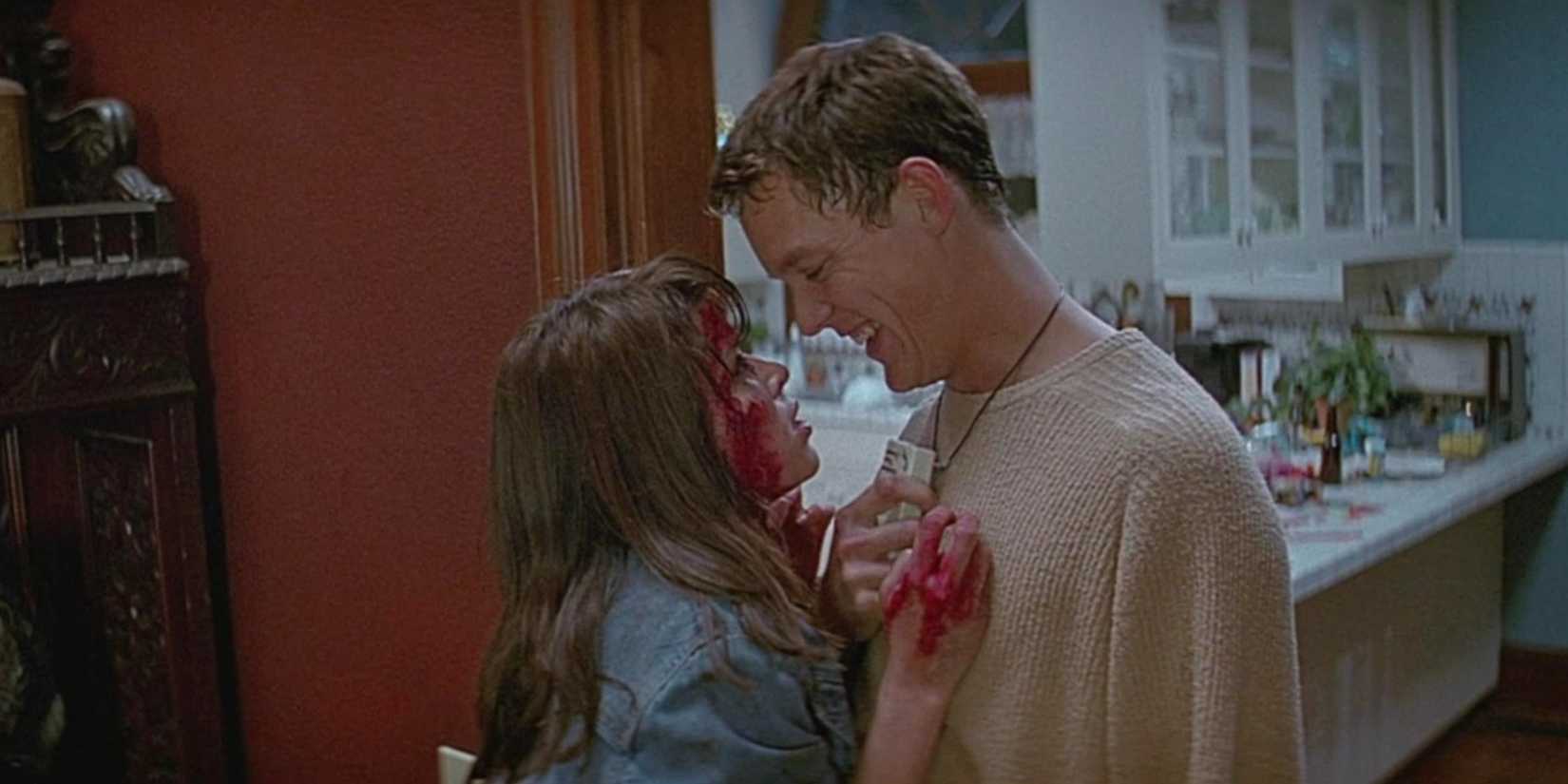 Neve Campbell as Sidney Prescott covered in blood and looking helplessly at Matthew Lillard as Stu Macher in Scream