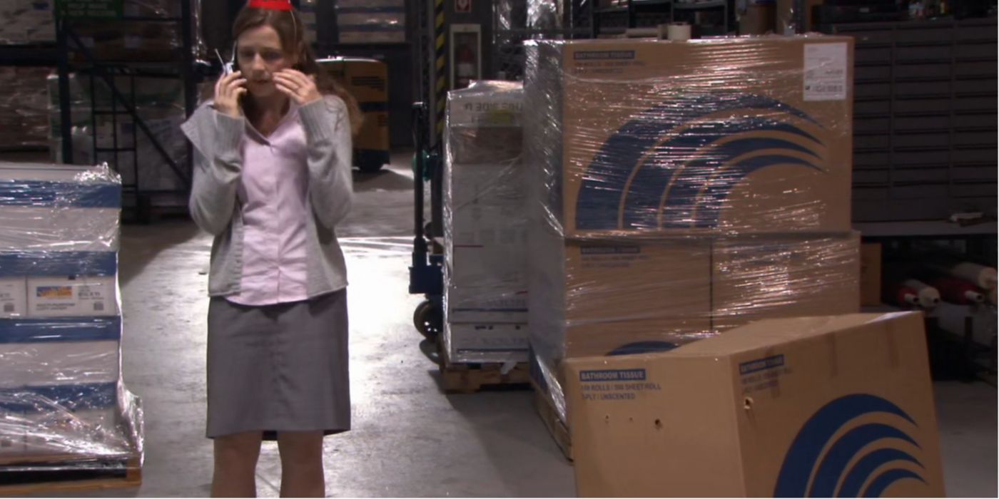 Pam Beesly talking on the phone as Dwight Schrute hides in a box in the warehouse on The Office